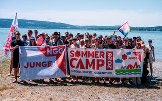 Foto von Menschen der jungeNGG mit einem Banner vor dem Bodensee stehend.
